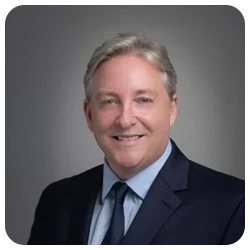 Dr Johnson smiling in a dark blue suit with matching tie.